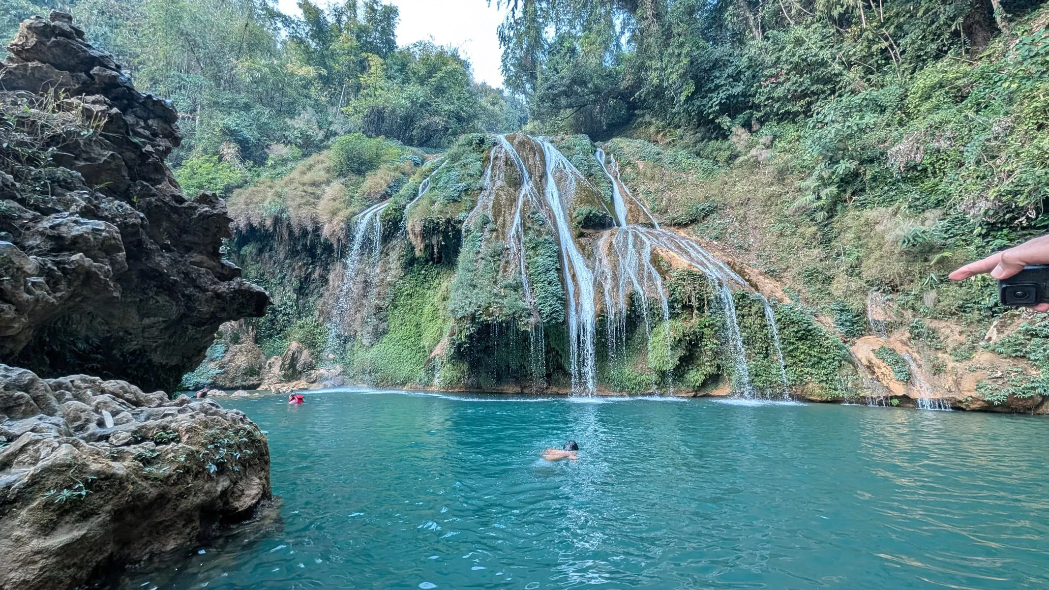 Krang Suri waterfall falling in white ribbons into a turquoise pool, with forest above