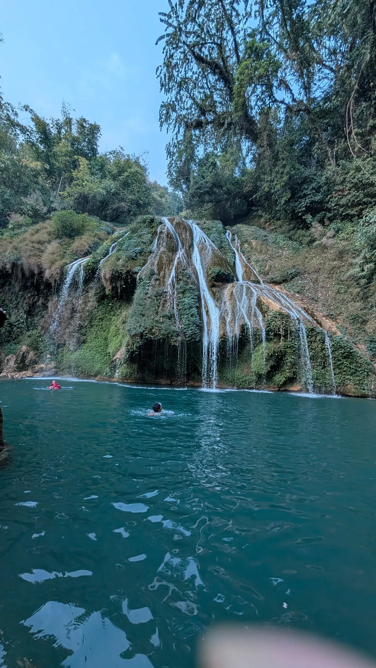 Swimmers in the blue pool below Krang Suri waterfall