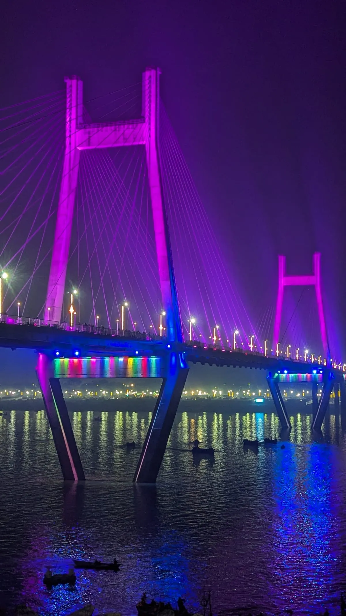 A cable-stayed bridge over the Yamuna, lit up in purple and pink at night
