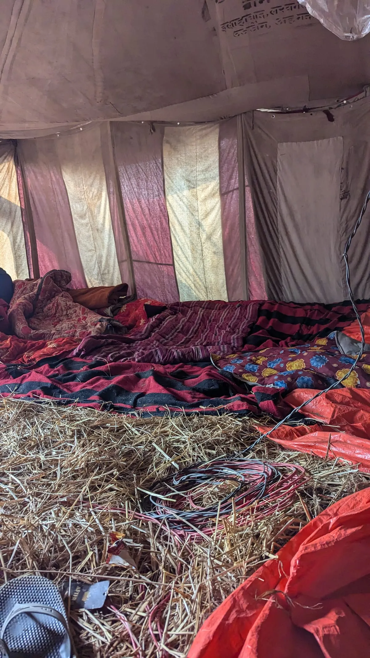 Inside a camp tent with a straw floor and blankets, in the morning